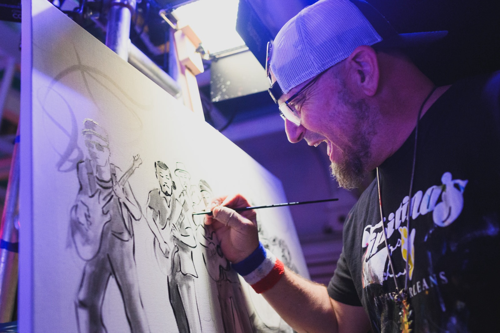 Frenchy laughing as he blocks in a band in black paint on a fresh canvas